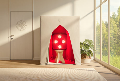 A compact SaunaSpace FireLight Infrared Sauna with red interior lighting and a stool is placed in a bright room featuring large windows, a plant, and a closed door.