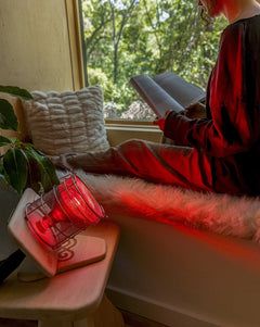 Woman reading in living room next to SaunaSpace Glow Infrared Therapy Light