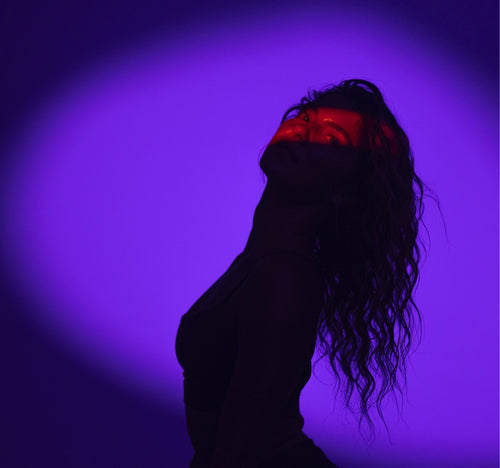 Woman in shadow lit by violet spotlight and red light