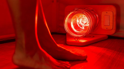 Woman's feet in FireLight Infrared Sauna in front of Glow Infrared Therapy Light that is on floor of sauna.