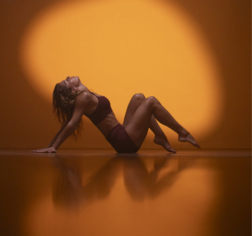 Woman in yoga pose lit by sunny spotlight