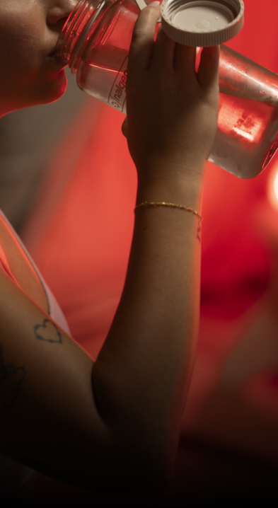 Woman drinking filtered water from bottle in preparation for her FireLight Infrared Sauna session