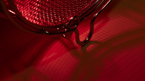 Close-up of a stainless steel mesh bulb guard of SaunaSpace light panel with FireLight bulb on.