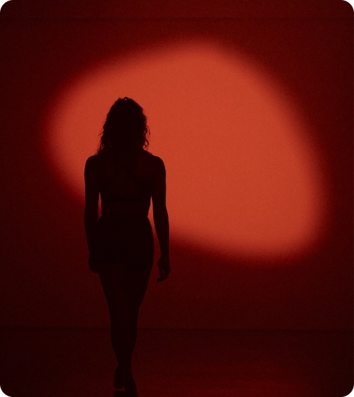 Silhouette of woman walking toward red spotlight background in dimly lit room