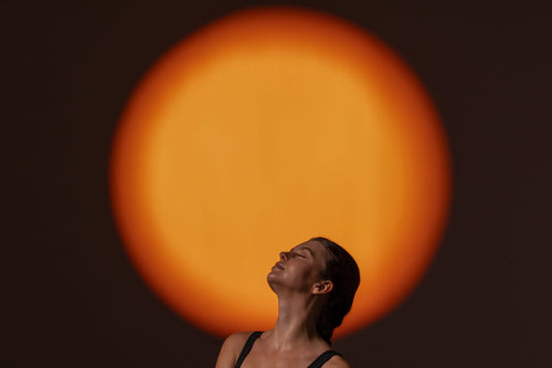 woman with light shining on her chest in standing yoga pose