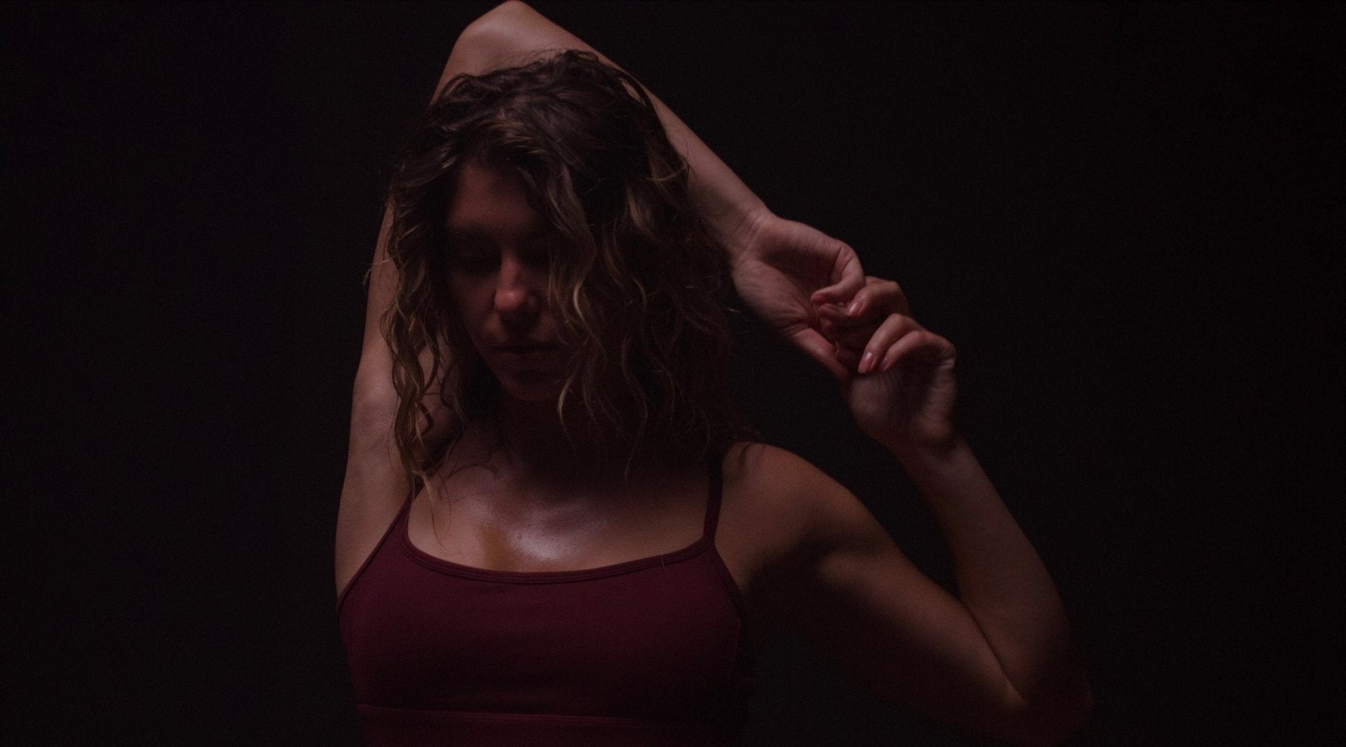 Fit woman is sweaty, and holding her hands in a beautiful graceful bind behind her head