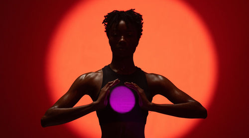 Silhouette of person holding a glowing purple sphere against an orange background