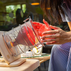 SaunaSpace Glow Infrared Therapy Light - A woman warms her hands around the incandescent Glow Light.