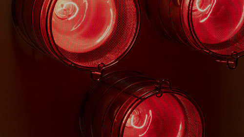 Close-up of a stainless steel mesh bulb faraday guard of SaunaSpace infrared light panel with FireLight bulb on.