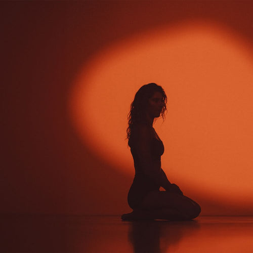 Silhouette of a woman kneeling against an orange background