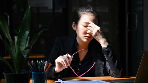 Tired and stressed woman working at computer holding head with hand