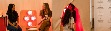 Two SaunaSpace Event Team Members sitting next to a Hearth Panel with a third  Team Member talking to a woman who sits in a FireLight Infrared Sauna, all in a SaunaSpace event booth
