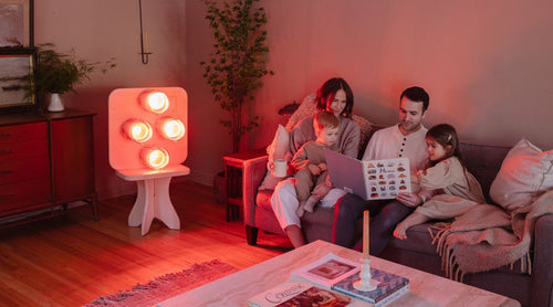 Family seated on couch in living room with Hearth Infrared Sauna Panel with lights on creating an infrared living room retreat