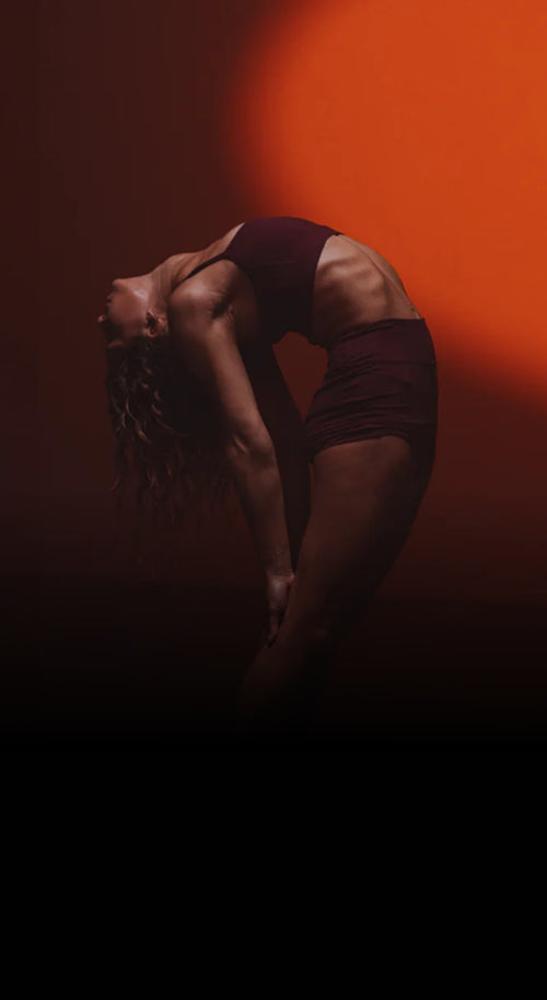 Person in a dark outfit against an orange background