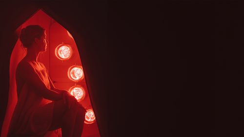 Woman sitting in FireLight Infrared Sauna on Sauna Stool with lights on and sauna entrance curtain open