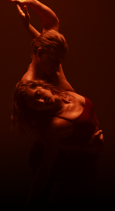 Man dancing with and holding woman in a dark glow of red light