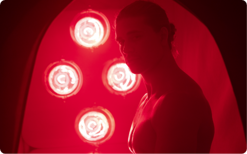 Muscular man looking out from inside of FireLight Infrared Sauna with lights on