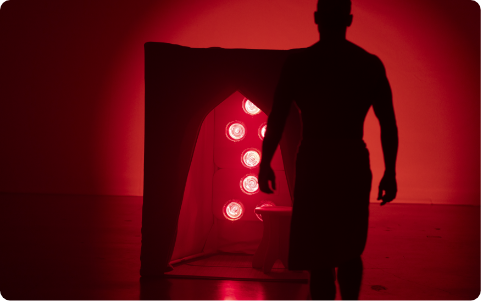 Silhouette of man walking toward FireLight Infrared Sauna with lights on