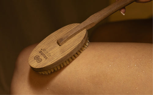 Woman using SaunaSpace Exfoliating Brush on her thigh